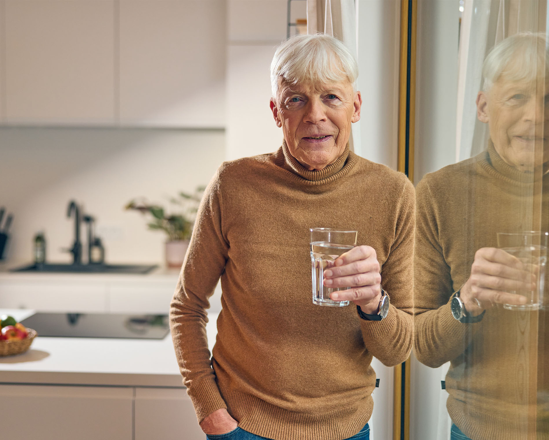 Ein älterer Herr hält ein Glas mit Wasser und einem Präparat in der Hand, das ihm hilft, die Beschwerden einer vergrößerten Prostata zu lindern
