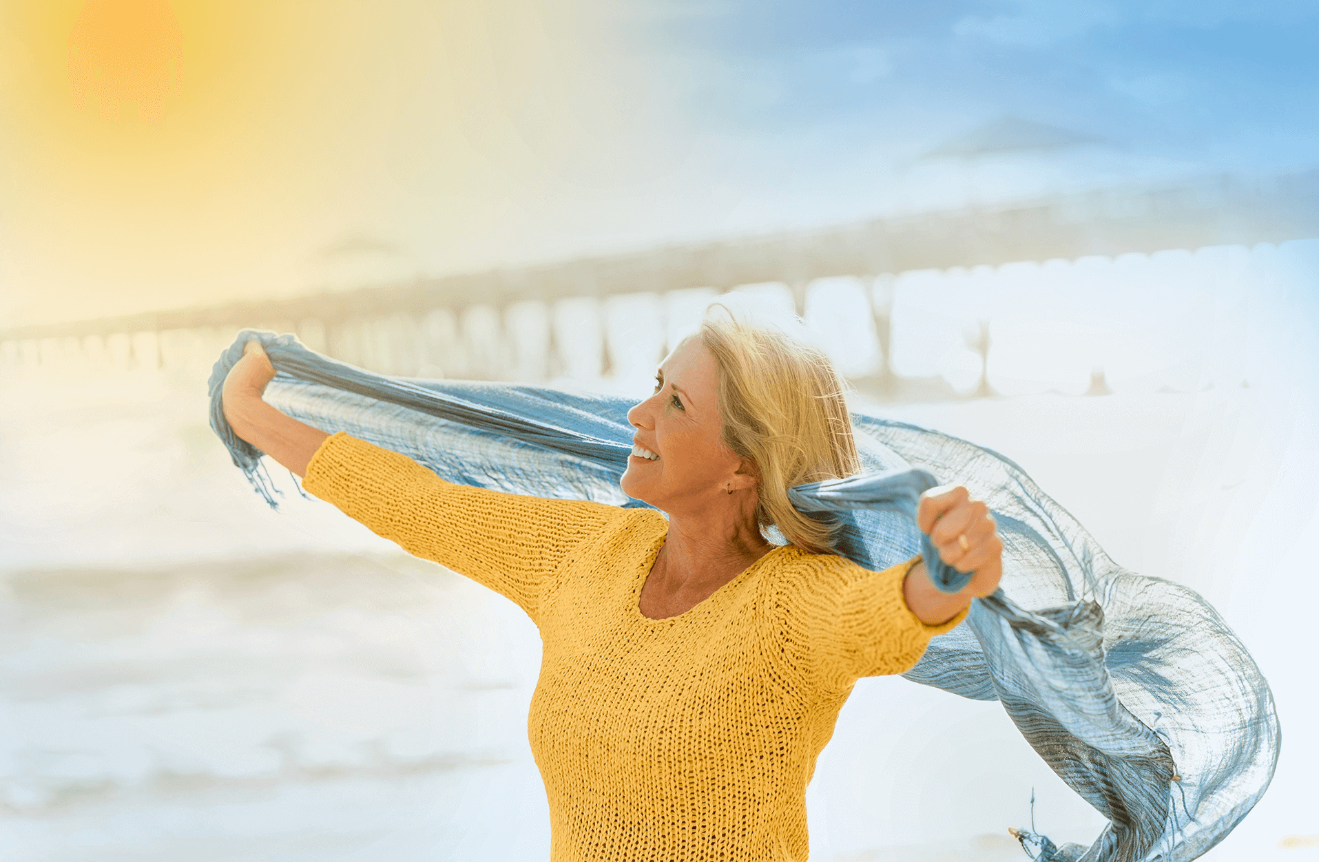 Frau ist ausgelassen am Strand, da sie ihre Blasenschwäche dank Therapie im Griff hat.