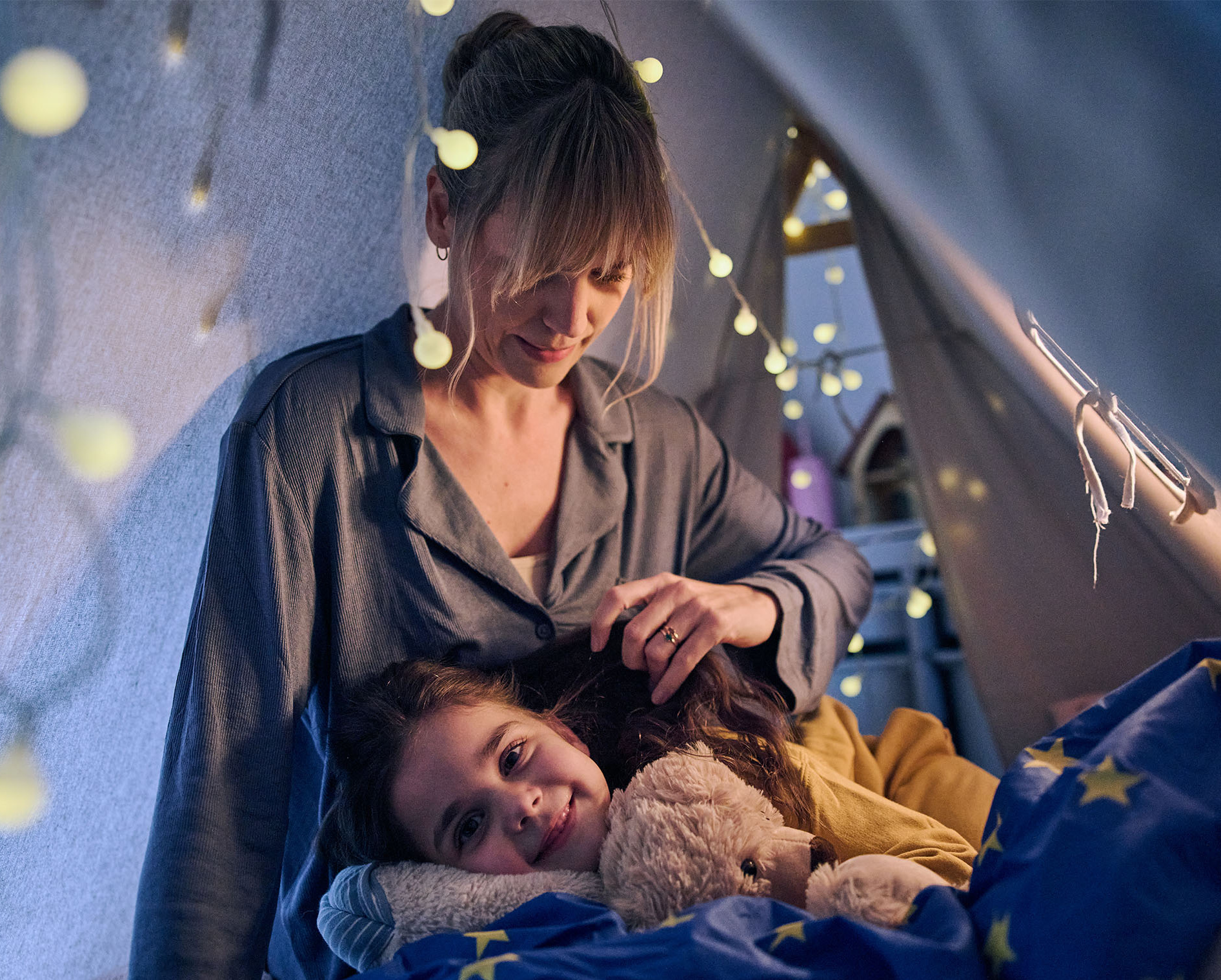 Mädchen liegt zum Einschlafen bei ihrer Mama und kuschelt