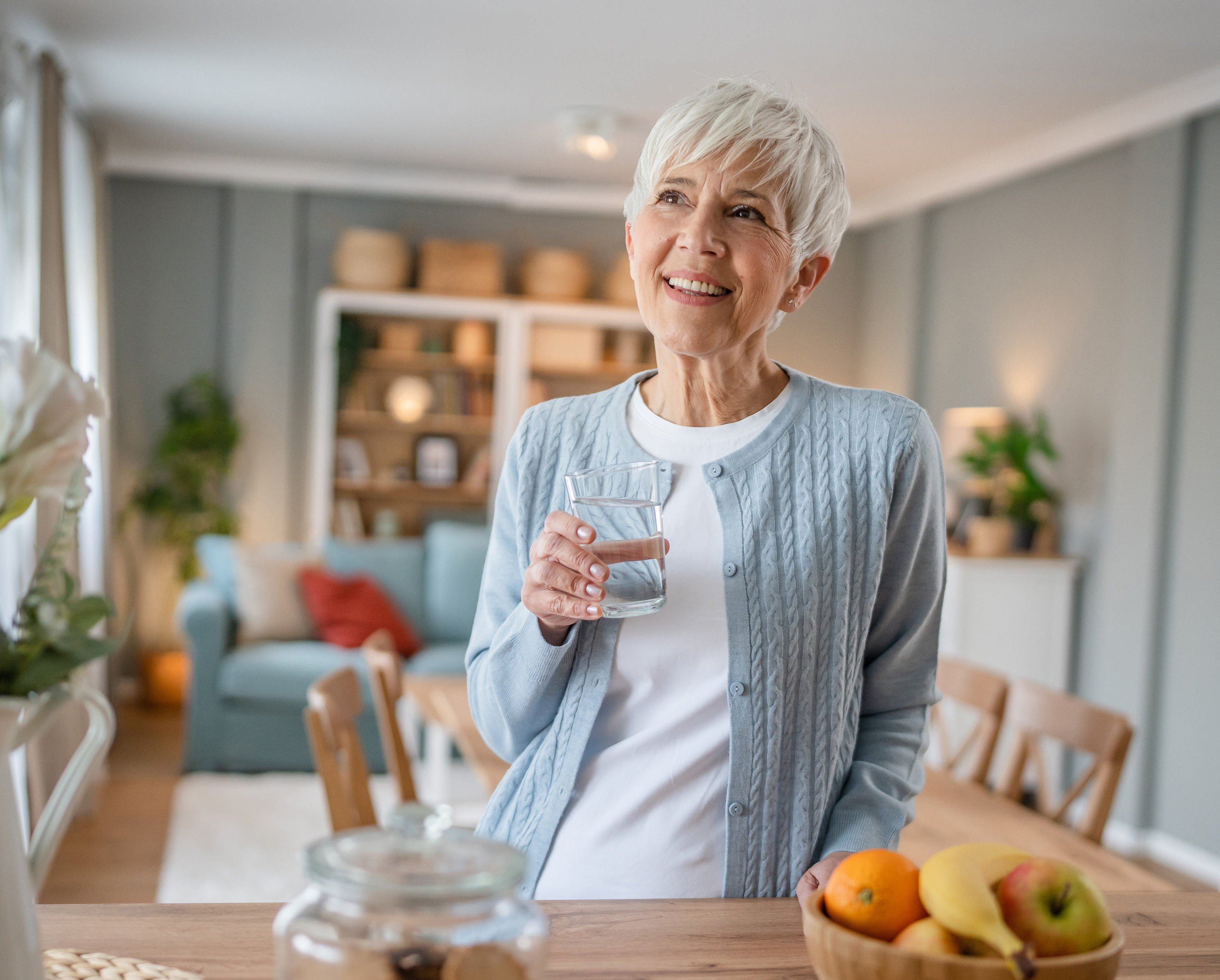 Frau mit Wasserglas in der Küche: Viel trinken kann gegen eine Reizblase helfen.