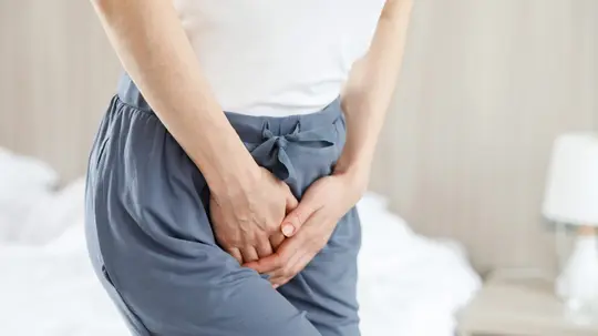 Harndrang: Frau hält sich die Hand an die Blase.