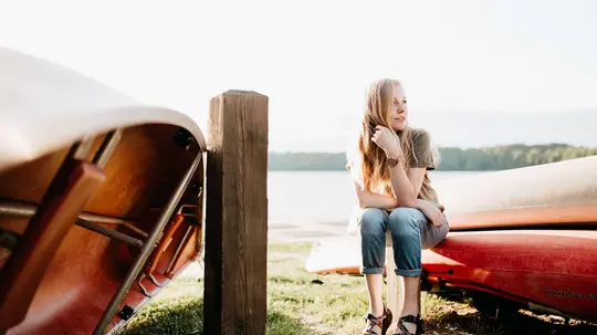 Frau sitzt an einem See auf einem Kanu