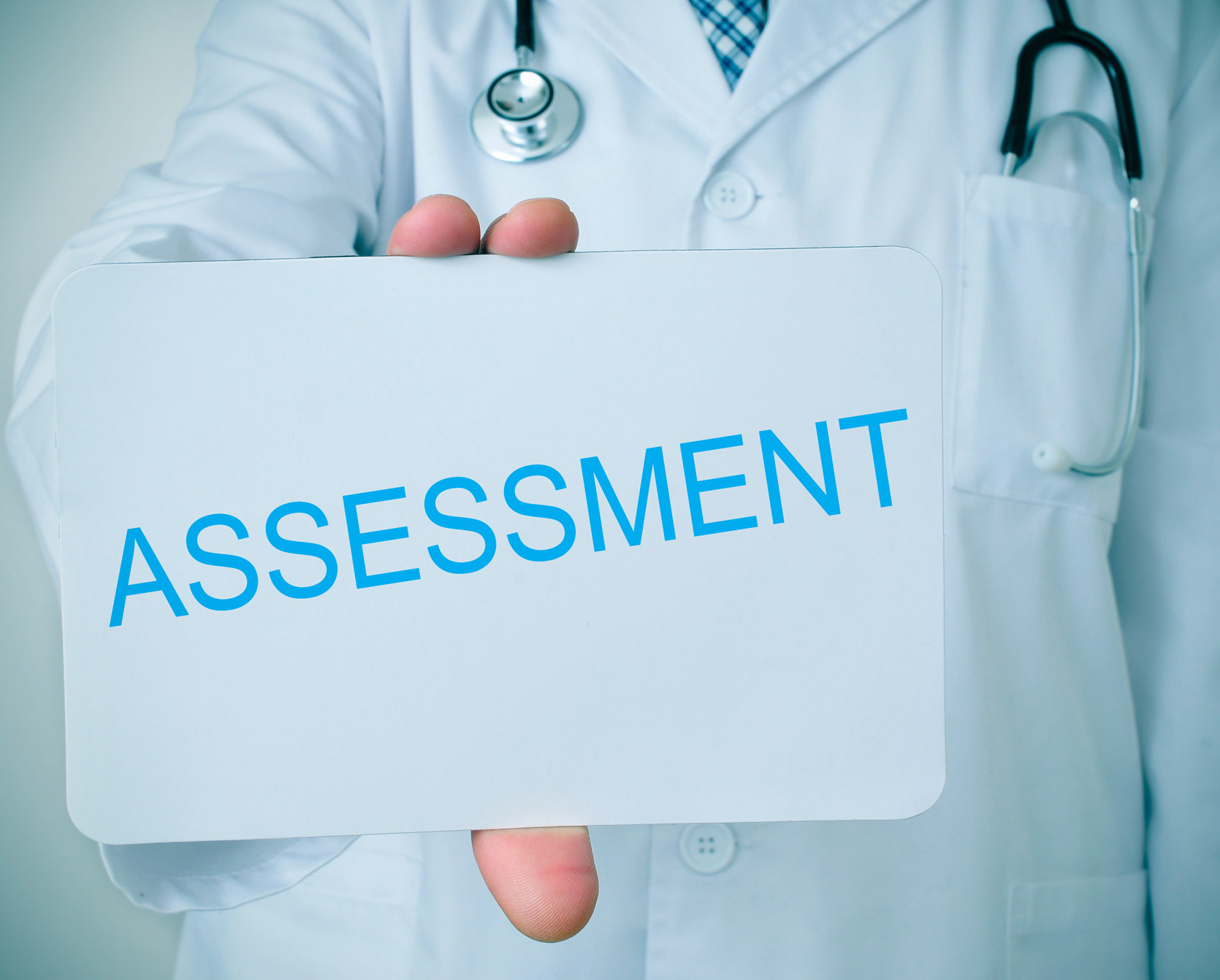 Arzt in einem weißen Kittel hält ein Schild in die Kamera, auf dem Assessment steht.