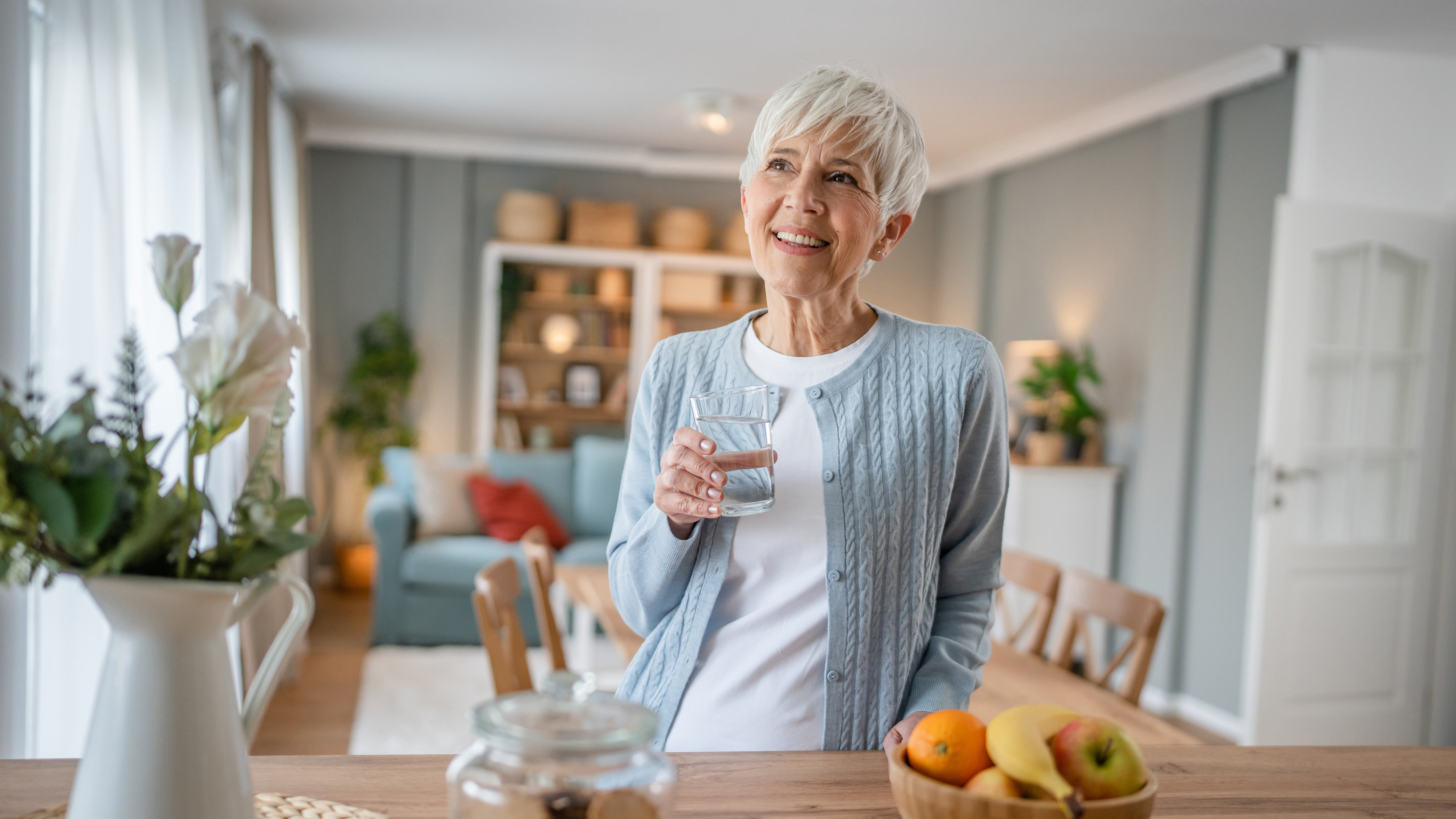 Frau mit Wasserglas in der Küche: Viel trinken kann gegen eine Reizblase helfen.